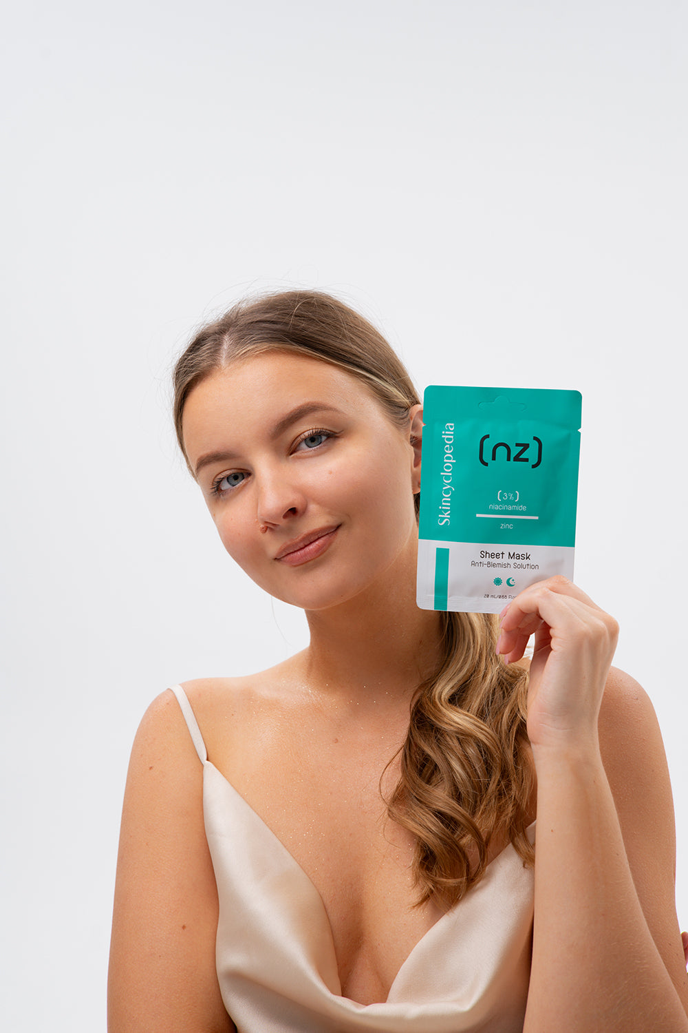 Frau hält Skincyclopedia Niacinamid Sheet Maske in der Hand. Die Maske ist grün und weiß. Fokus auf Porenverfeinerung und Klärung.