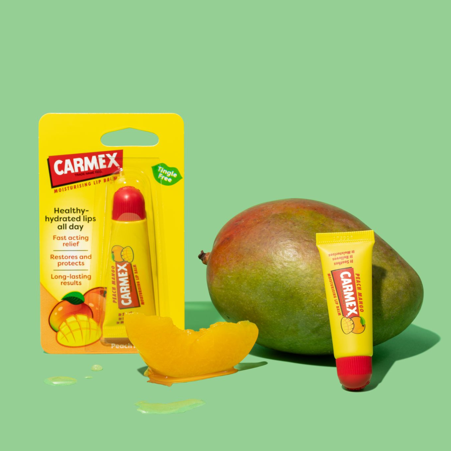 Gelbe Carmex Tube Pfirsich Mango Lippenbalsam, unverpackt & in Verpackung, daneben Mango Frucht und Mangostück.