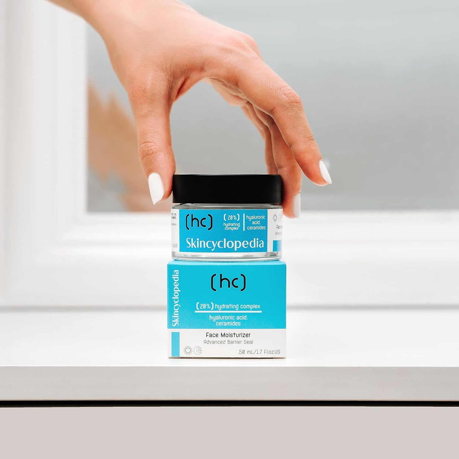 Hand hält SKINCYCLOPEDIA Feuchtigkeitscreme über der blauen Verpackung. Die Creme verspricht intensive Hydration mit 20% Hydrating Complex.