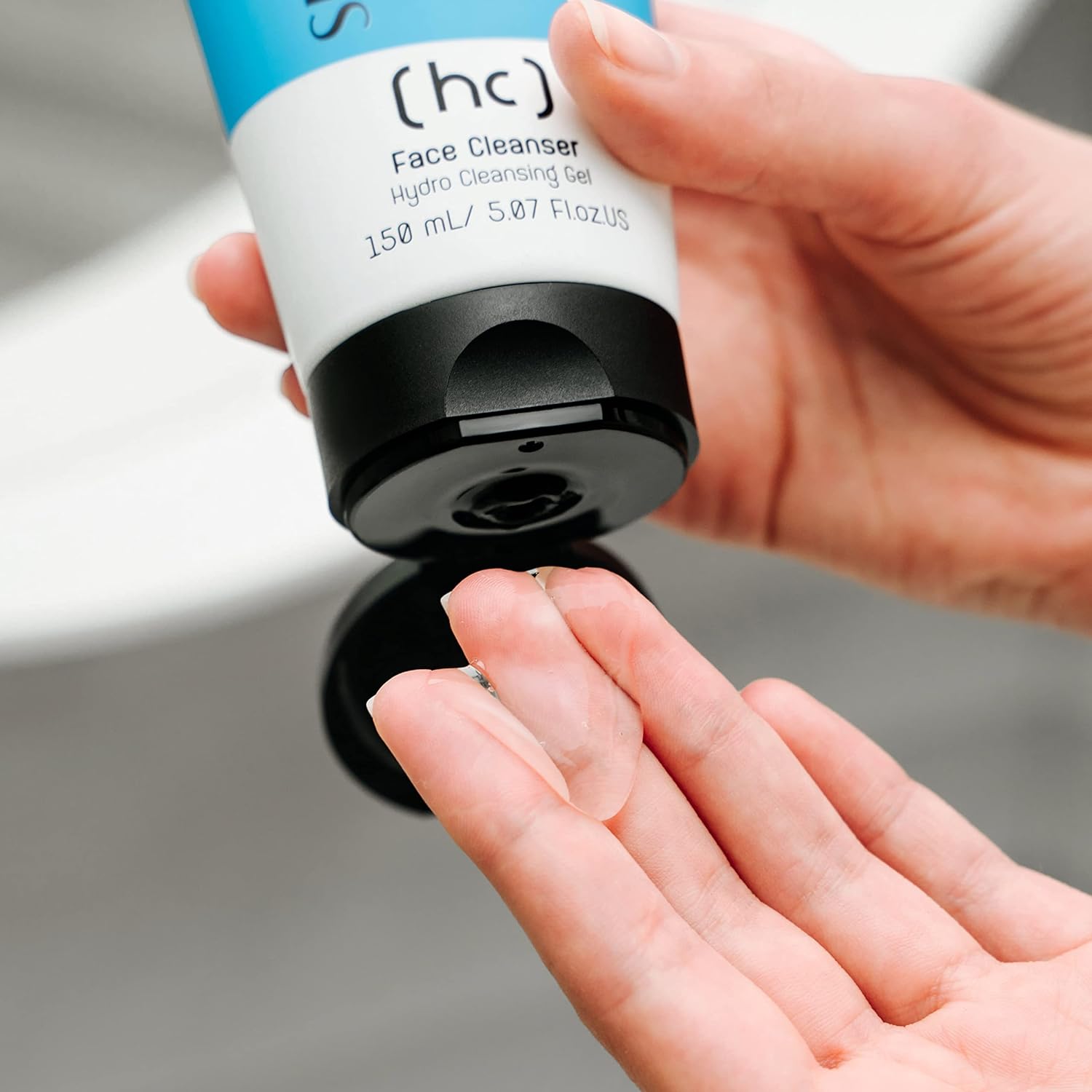 Ein SKINCYCLOPEDIA Gesichtsreiniger wird auf die Hand gegeben. Die durchsichtige Gel-Textur ist gut erkennbar. Die Tube ist weiß mit blauem Akzent.