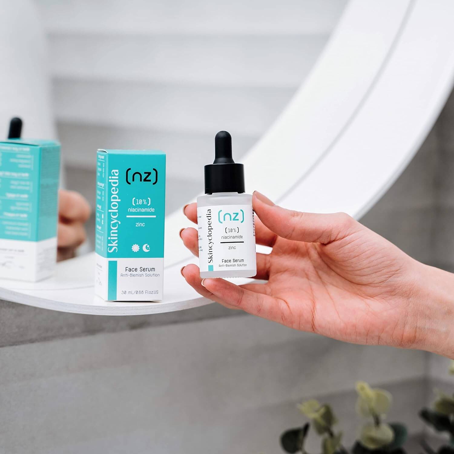 Ein Gesichtsserum mit Niacinamid und Zink in einer Hand, Produktverpackung im Hintergrund. Serum zur Porenverfeinerung für eine ausgeglichene Haut.