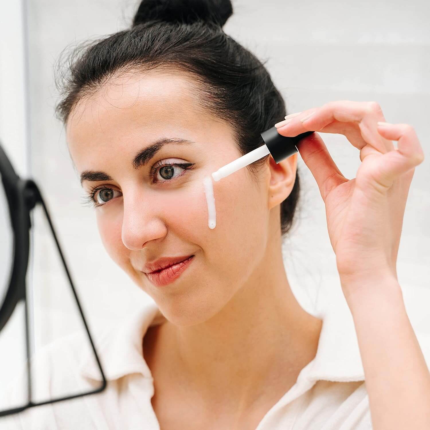 Frau trägt Ceramide Serum mit Pipette auf die Wange auf. Fokus auf Hautpflege und Anwendung des Serums.