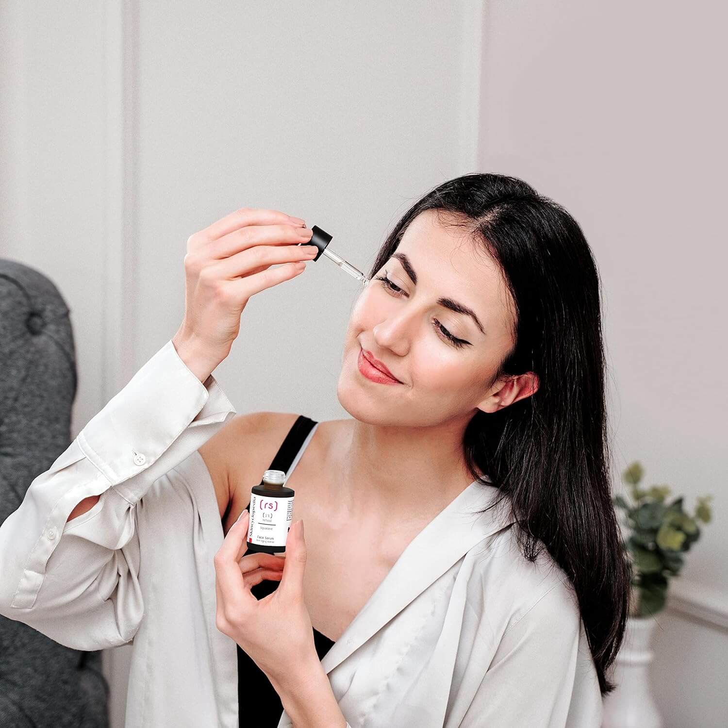 Frau trägt Retinol Serum mit Pipette auf. Produktflasche mit Etikett wird gezeigt. Fokus auf Anti-Aging und Glättung.