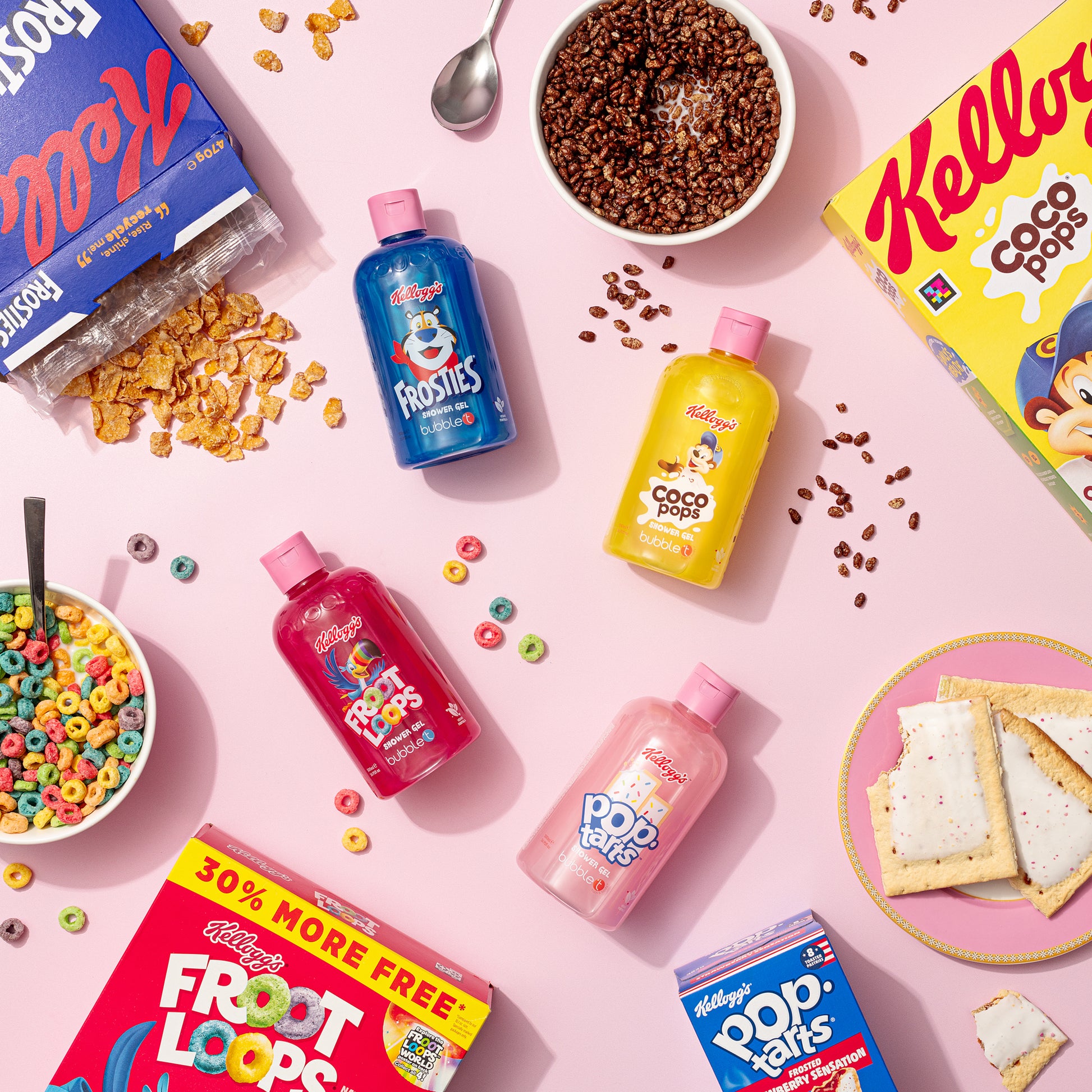 Flach gelegte Kellogg's Duschgel-Flaschen (Frosties), Cerealien und Pop Tarts auf rosa Grund. Frosted Flakes, Froot Loops und Coco Pops sind auch sichtbar.