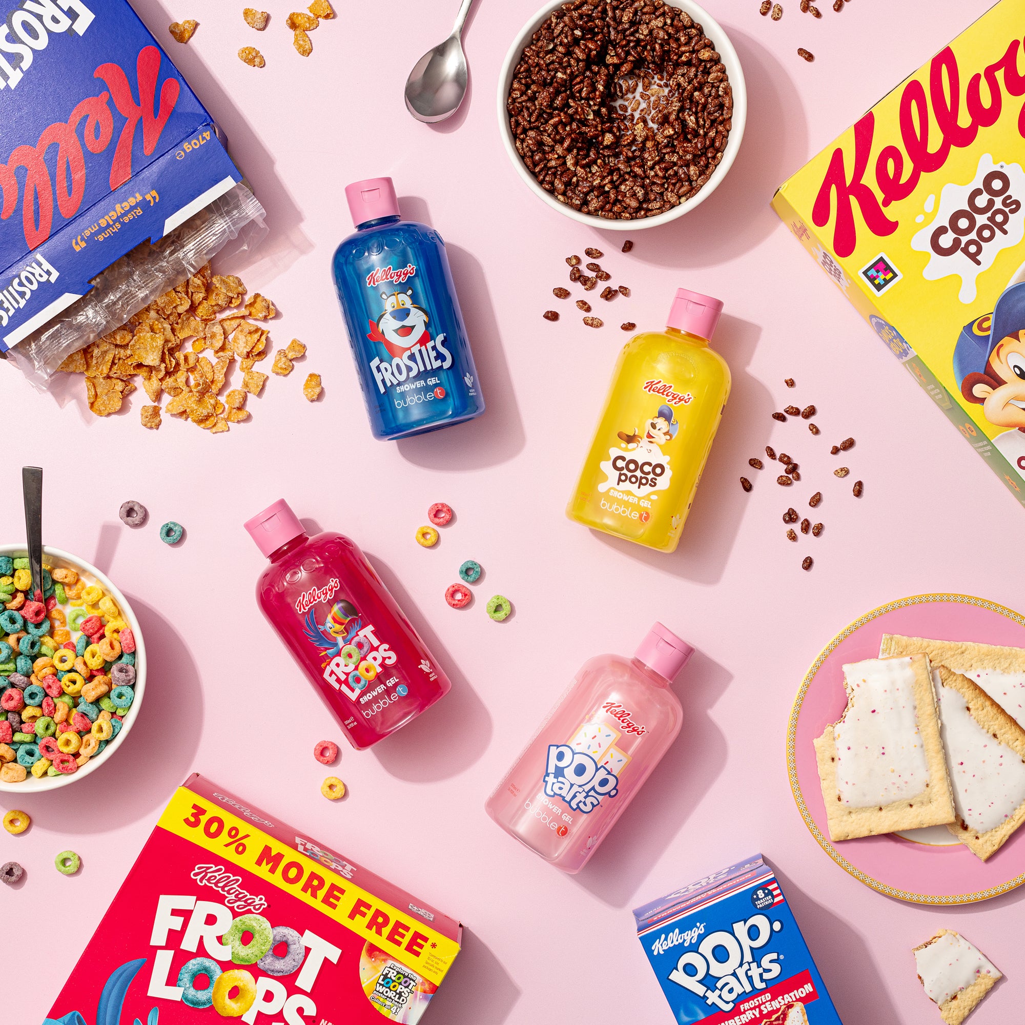Flach gelegte Kellogg's Duschgel-Flaschen (Frosties), Cerealien und Pop Tarts auf rosa Grund. Frosted Flakes, Froot Loops und Coco Pops sind auch sichtbar.