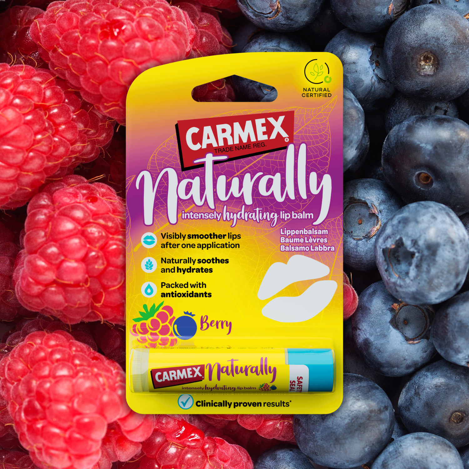 Verpackung Carmex Naturally Berry Lippenbalsam im Stick-Format. Hintergrund sind Himbeeren und Blaubeeren. Die Verpackung ist gelb und lila.