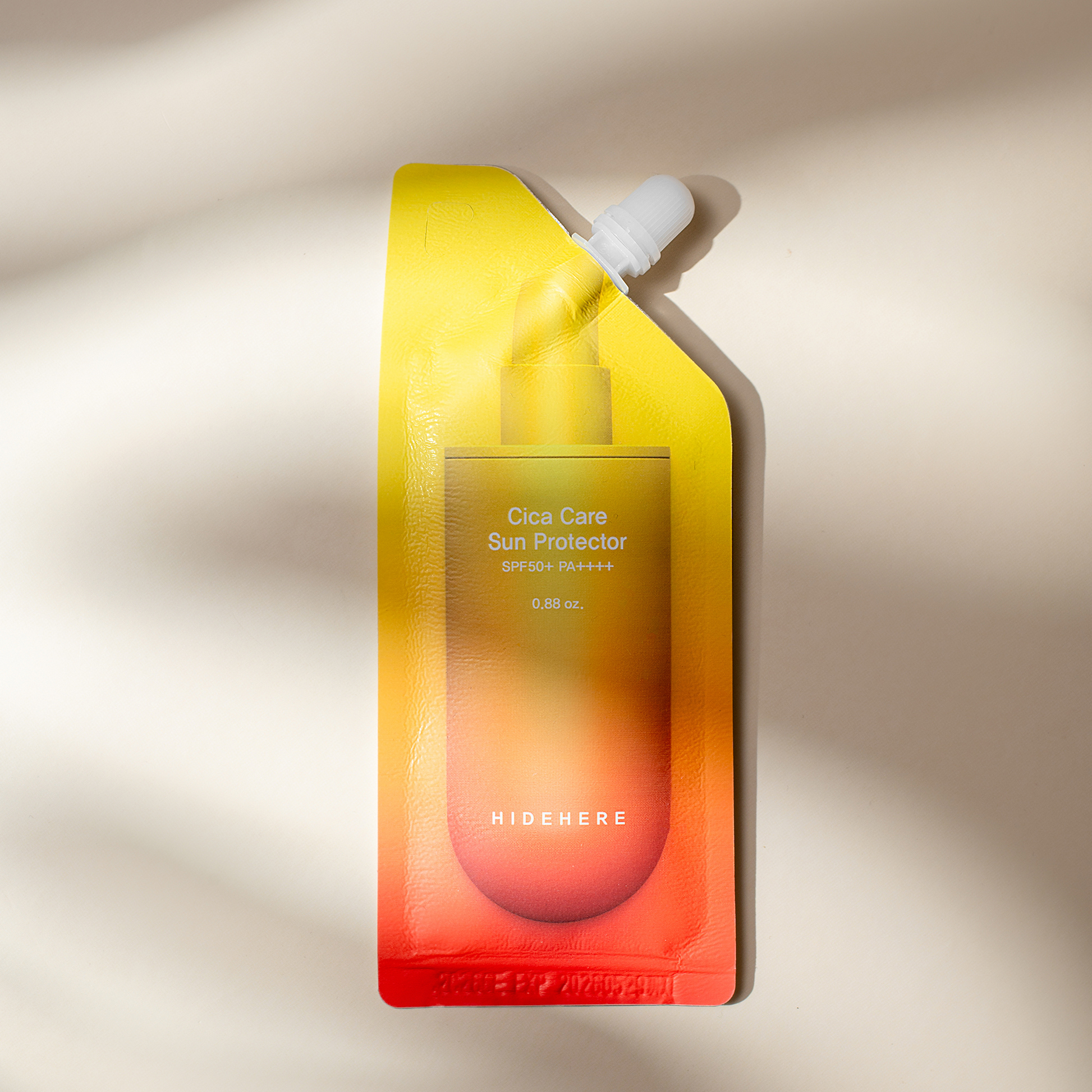 Eine Packung Cica Care Sun Protector liegt auf einer weißen Fläche. Die Packung ist oben leuchtend gelb und geht unten in Orange und Rot über, mit weißer Schrift auf der Vorderseite. Auf der Oberseite befindet sich eine weiße Kappe.
