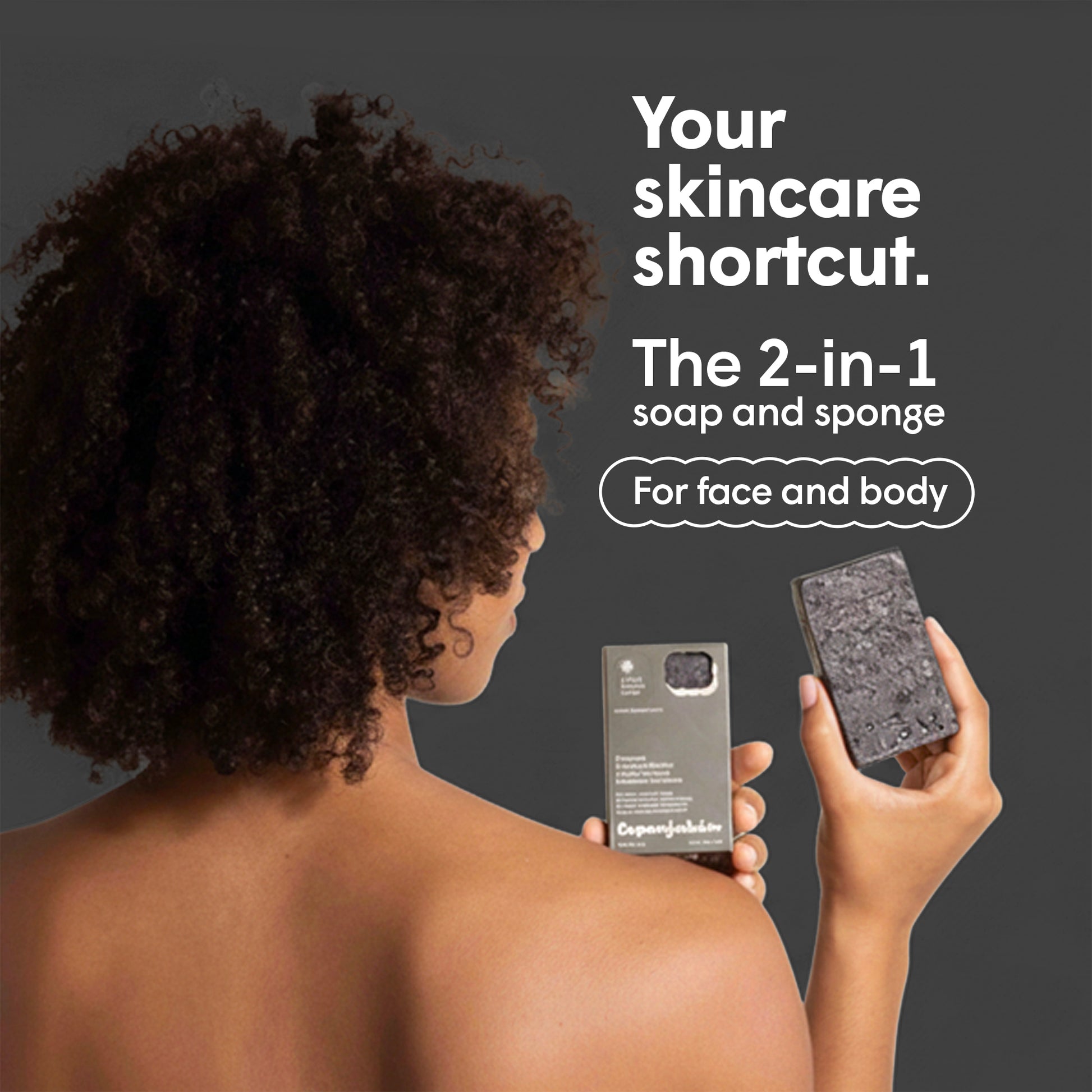 Eine Frau mit Afro hält eine Verpackung und ein Stück dunkle Seife vor einer grauen Fläche. Text neben der Frau wirbt für eine 2-in-1 Seife mit Schwamm für Gesicht und Körper.