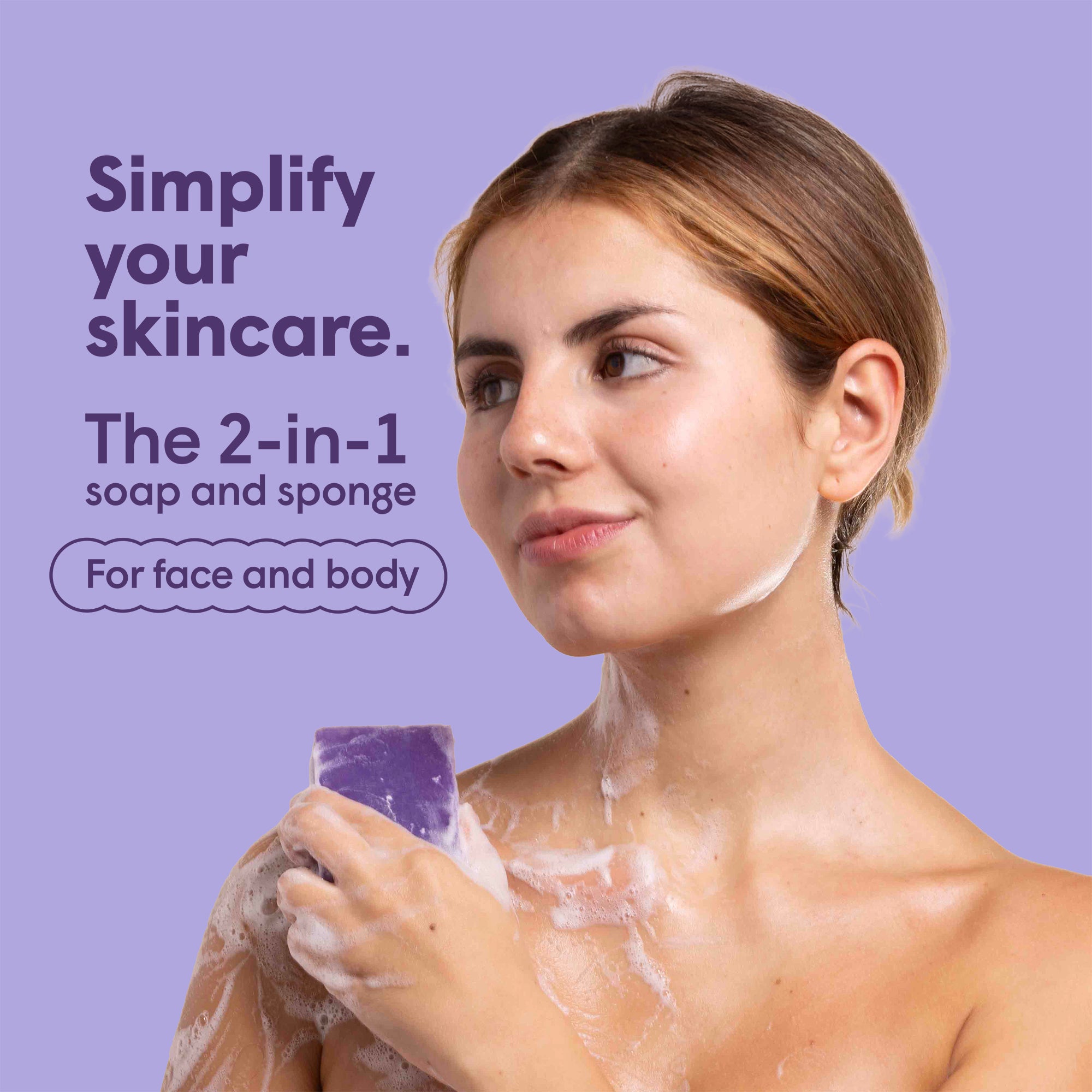 Porträt einer Frau, die sich mit lila Seife und Schwamm wäscht. Seifenschaum bedeckt ihre Haut. Text: "Simplify your skincare. The 2-in-1 soap and sponge. For face and body".