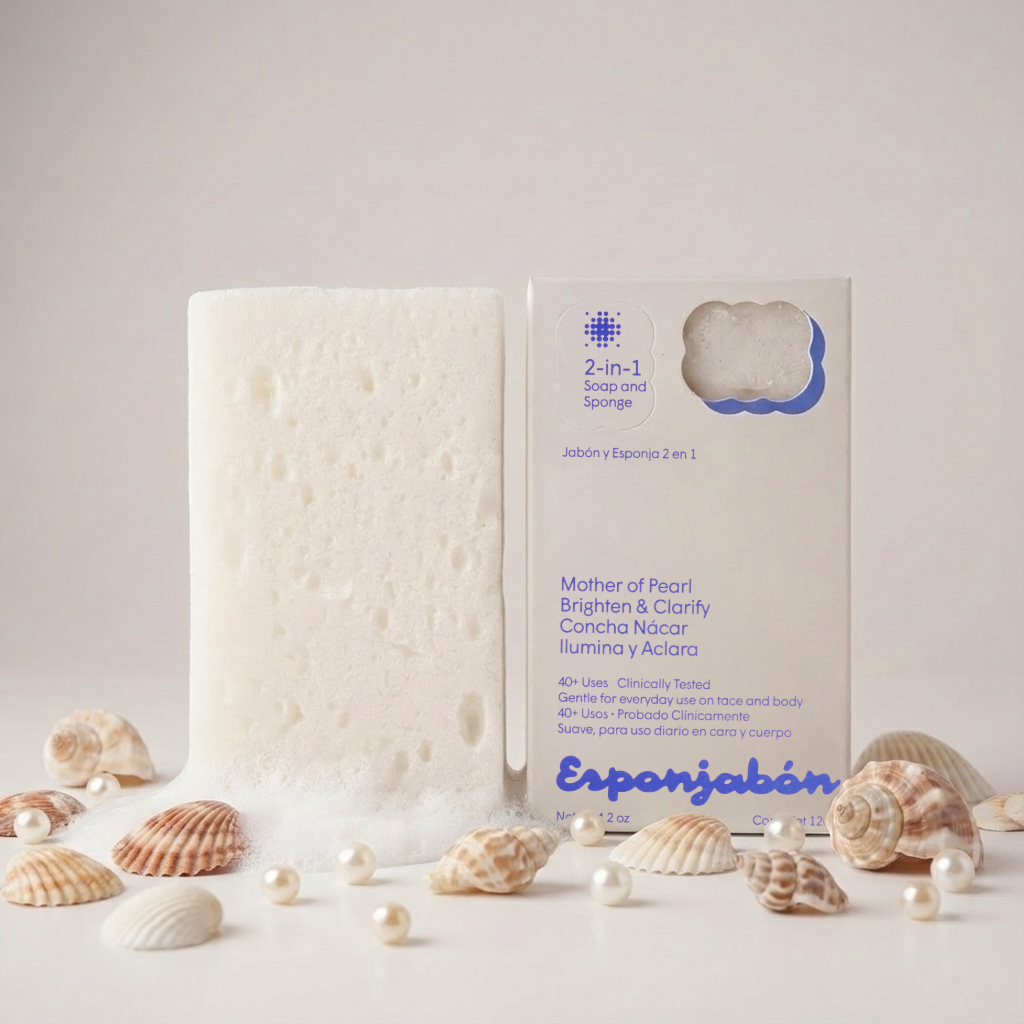 Ein 2-in-1 Seifen-Schwamm-Produkt neben einer weißen Schachtel mit Muscheln und Perlen auf einem Tisch.