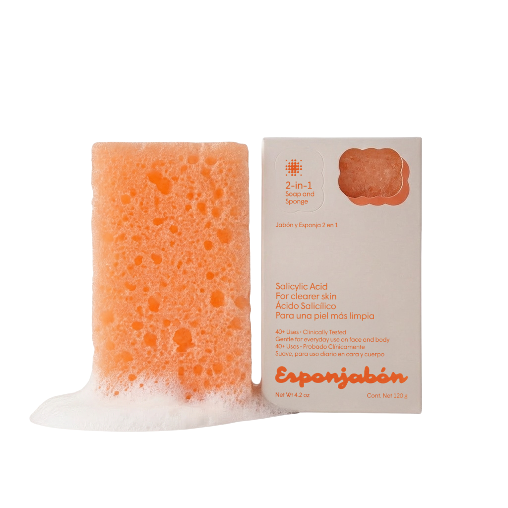 Oranger Badeschwamm mit Seife neben der Produktverpackung. Text auf der Packung ist auf Englisch und Spanisch.