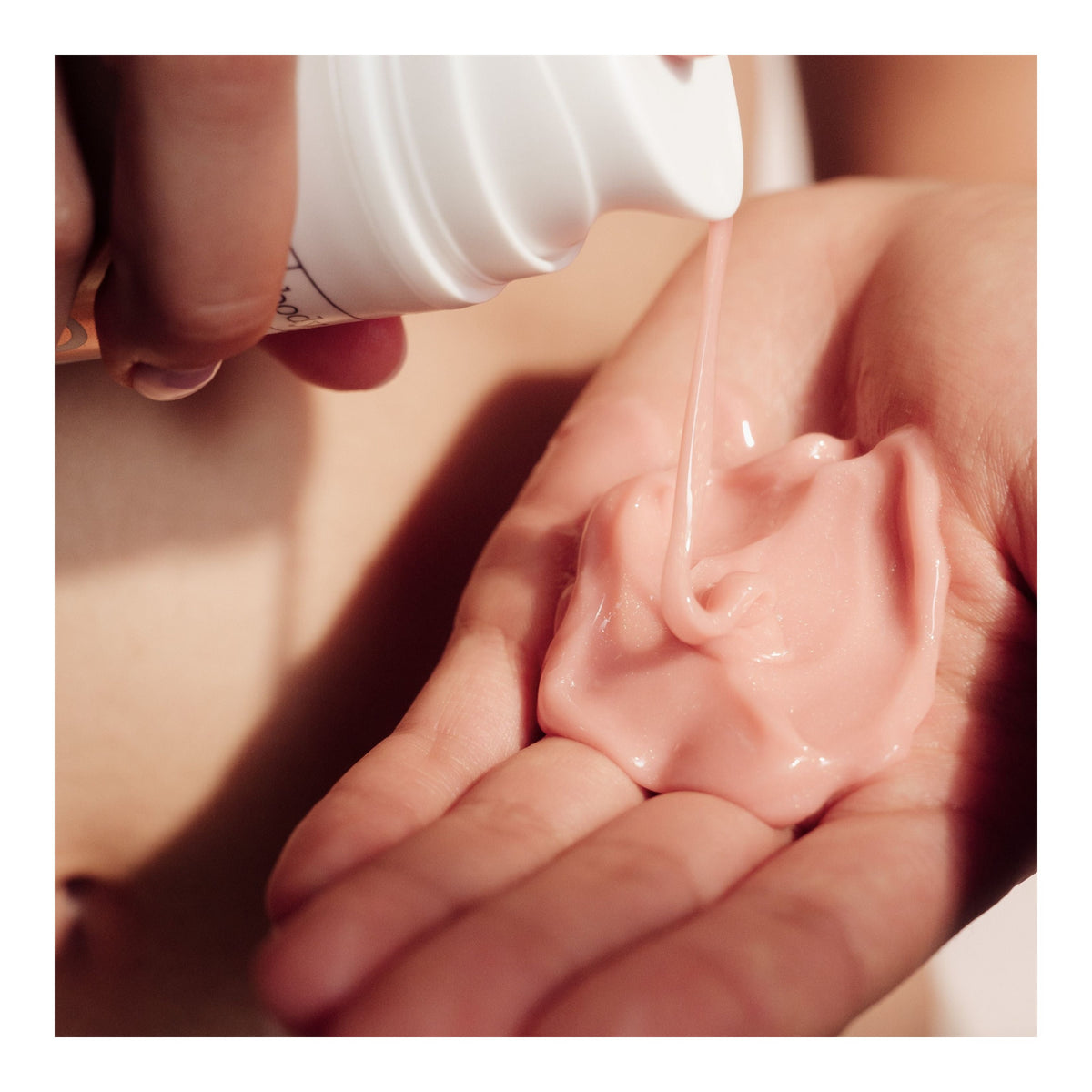 La crème rose du kit « Glazed Buns » de FRANK BODY est versée dans la paume de la main à l'aide d'un flacon pompe blanc