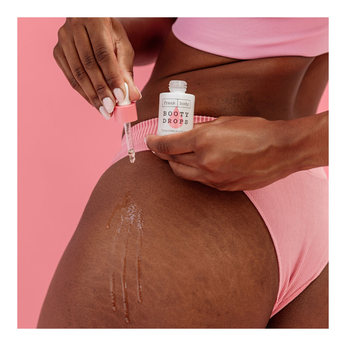 Une personne applique l'huile pour le corps contenue dans le kit « Glazed Buns » de FRANK BODY à l'aide d'une pipette sur la peau de la cuisse