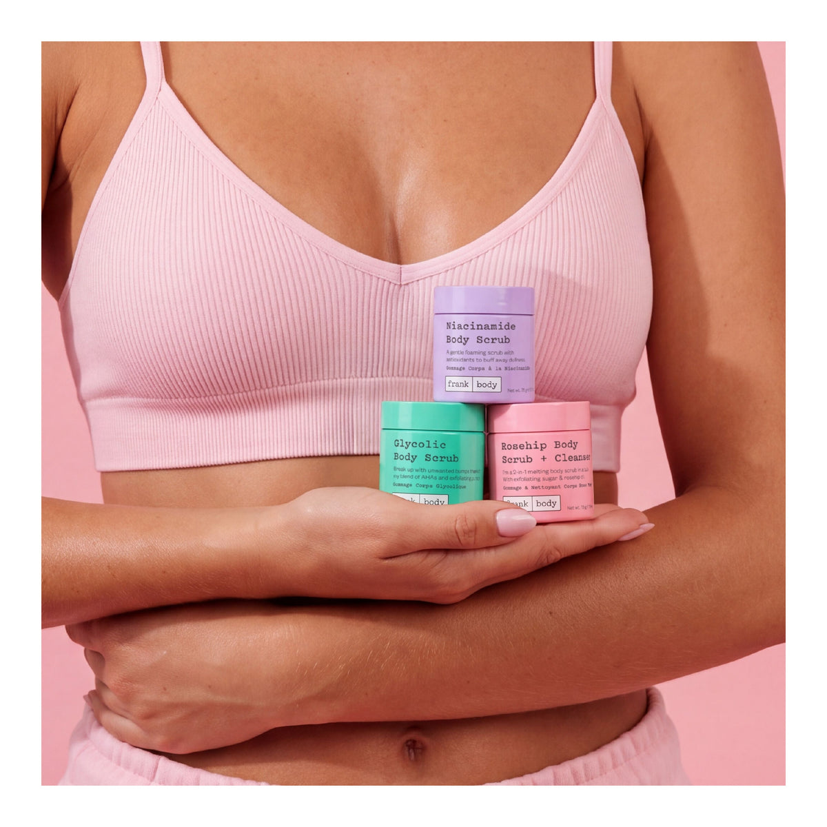 Drei bunte Tiegel des FRANK BODY Three-Way Kit in der Hand einer Frau vor rosa Hintergrund
