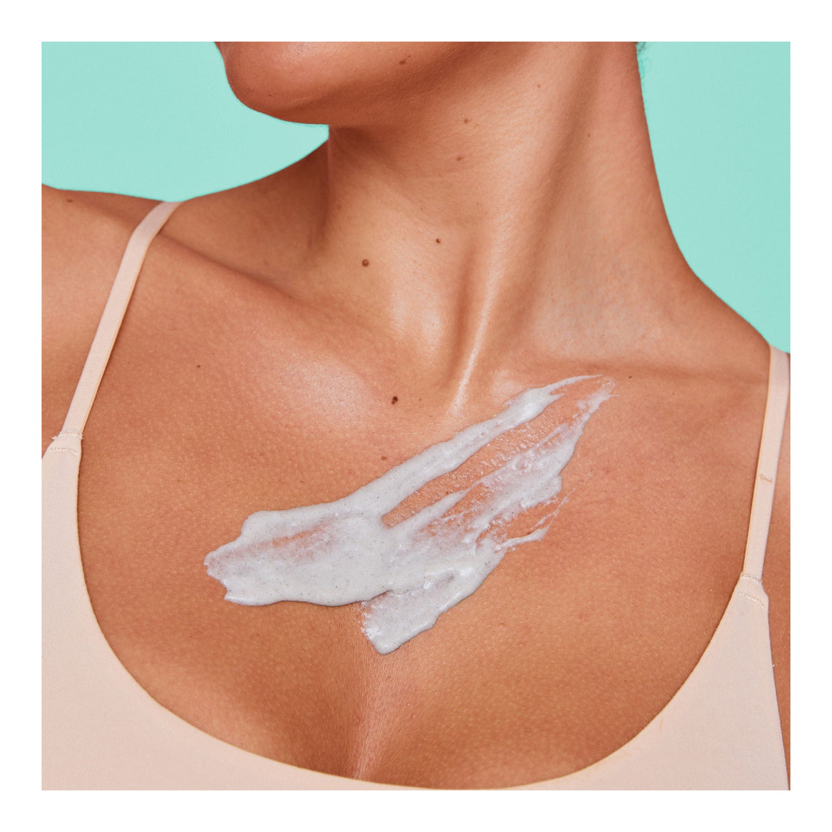 Cremiges Körperpeeling aus dem FRANK BODY Three-Way Kit auf dem Dekolleté einer Frau aufgetragen