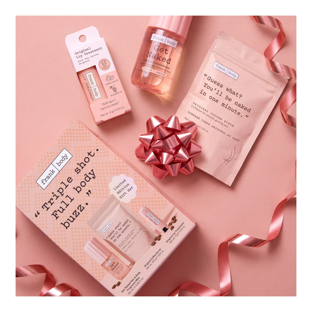 FRANK BODY Triple Shot Kit Geschenkset mit Lippenpflege, Kaffeepeeling, Körperspray und rosa Schleife auf pinkem Grund