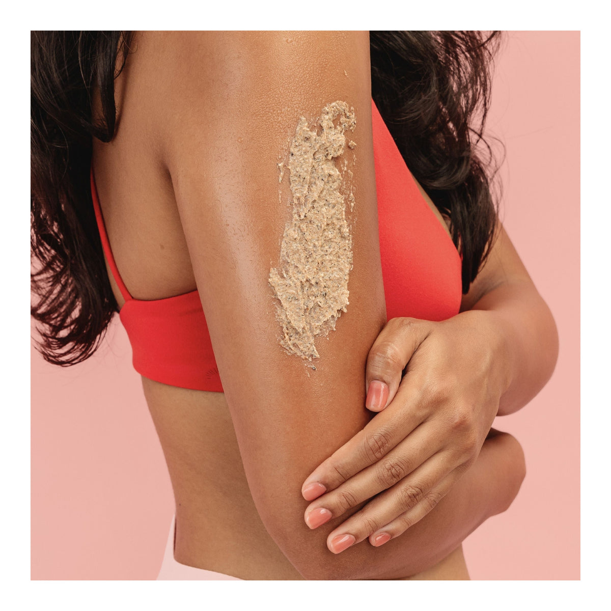 Peeling-Textur aus dem FRANK BODY You'll Be Whipped Kit auf dem nassen Oberarm einer Frau vor rosa Hintergrund