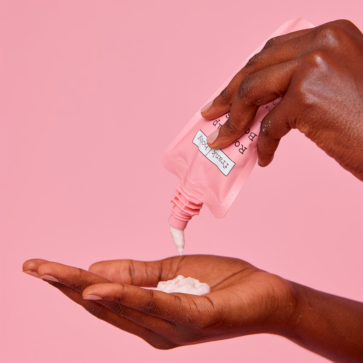 FRANK BODY Rosehip Body Scrub + Cleanser wird aus einer rosa Tube auf eine Handfläche gedrückt