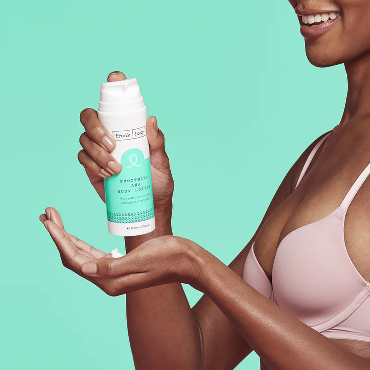Eine Frau gibt FRANK BODY Smoothing AHA Body Lotion aus dem Pumpspender auf ihre Hand vor türkisem Hintergrund