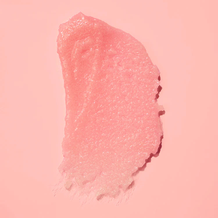 Körnige Texturprobe des rosafarbenen FRANK BODY Rosehip Body Scrub + Cleanser auf rosa Hintergrund