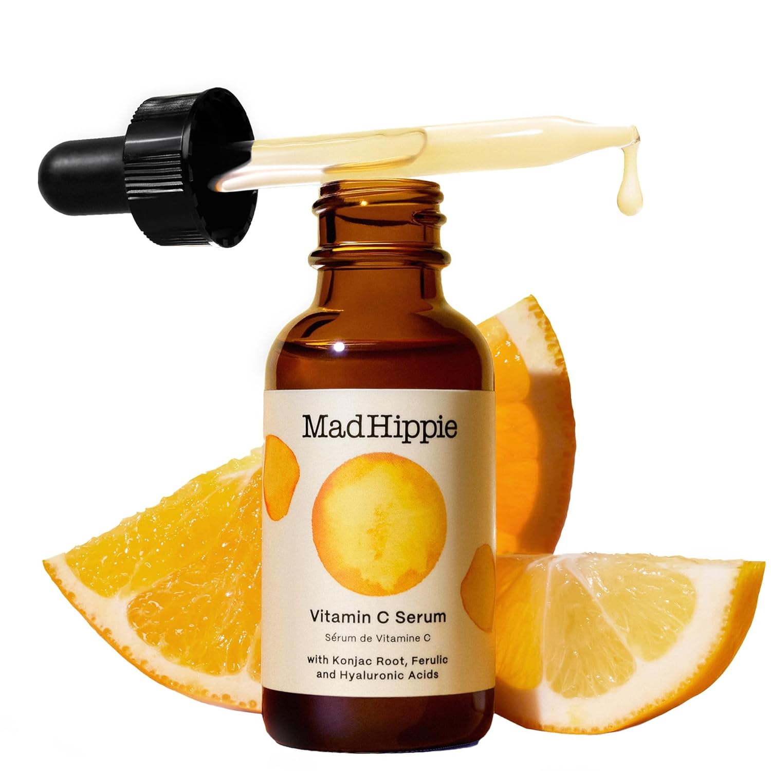 Braune Glasflasche mit Serum und Pipette, umgeben von Orangenscheiben. Etikett mit Aufschrift "Mad Hippie Vitamin C Serum".