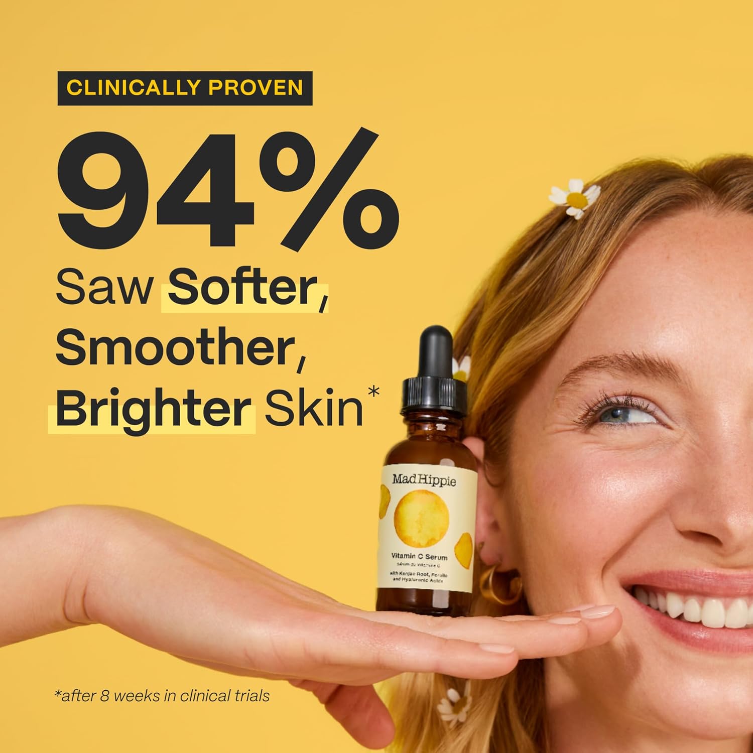 Uma mulher sorridente apresenta o sérum de vitamina C MAD HIPPIE na palma da mão, contra um fundo amarelo