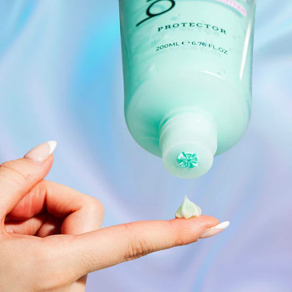Eine Hand hält einen Finger, auf dem ein kleiner Tropfen eines Produkts aus einer Tube mit der Aufschrift "Protector" ist. Die Tube ist türkisfarben. Der Hintergrund ist hellblau und lila.